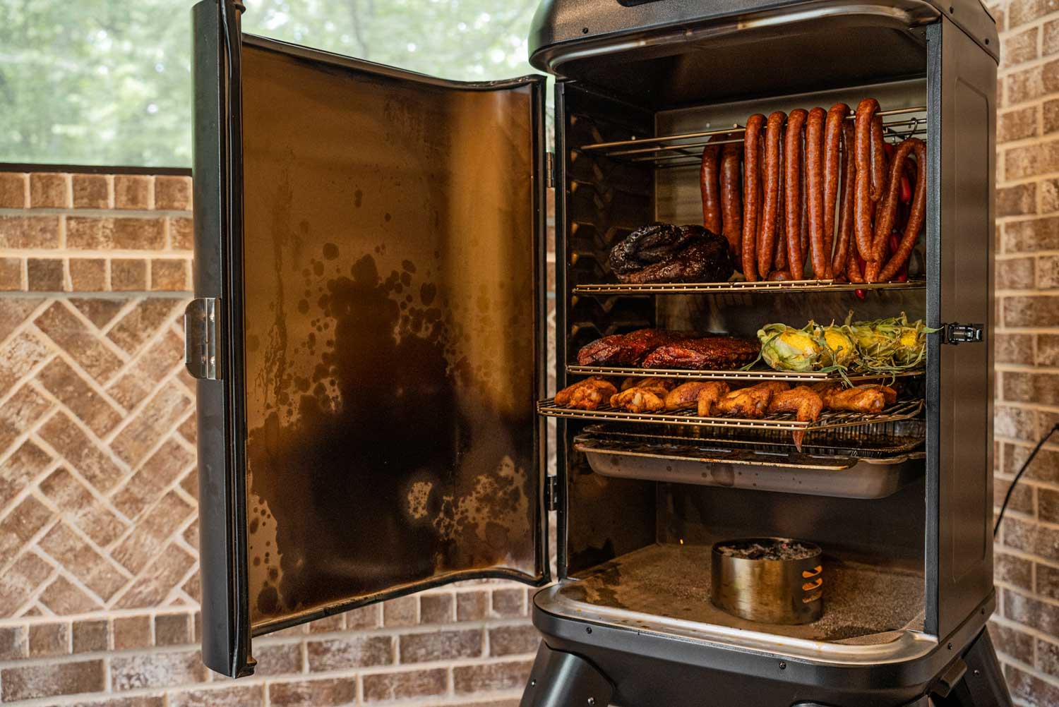 Mammoth vertical pellet smoker filled with hanging sausage, vegetables and chickens 